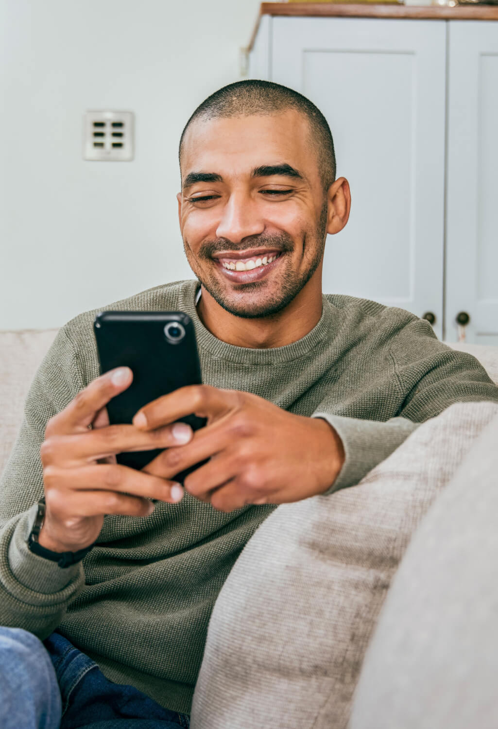 Man sitting on couch, viewing his smartphone