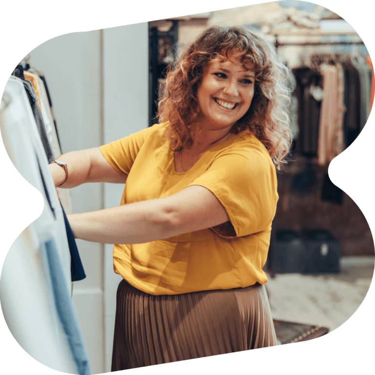 A woman in yellow shirt looking at clothes in a store