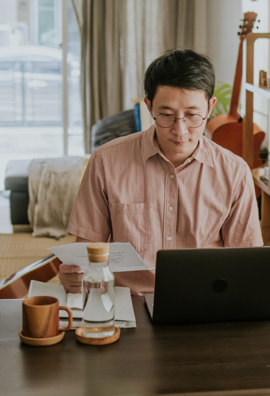 Man at a home desk with water and a laptop