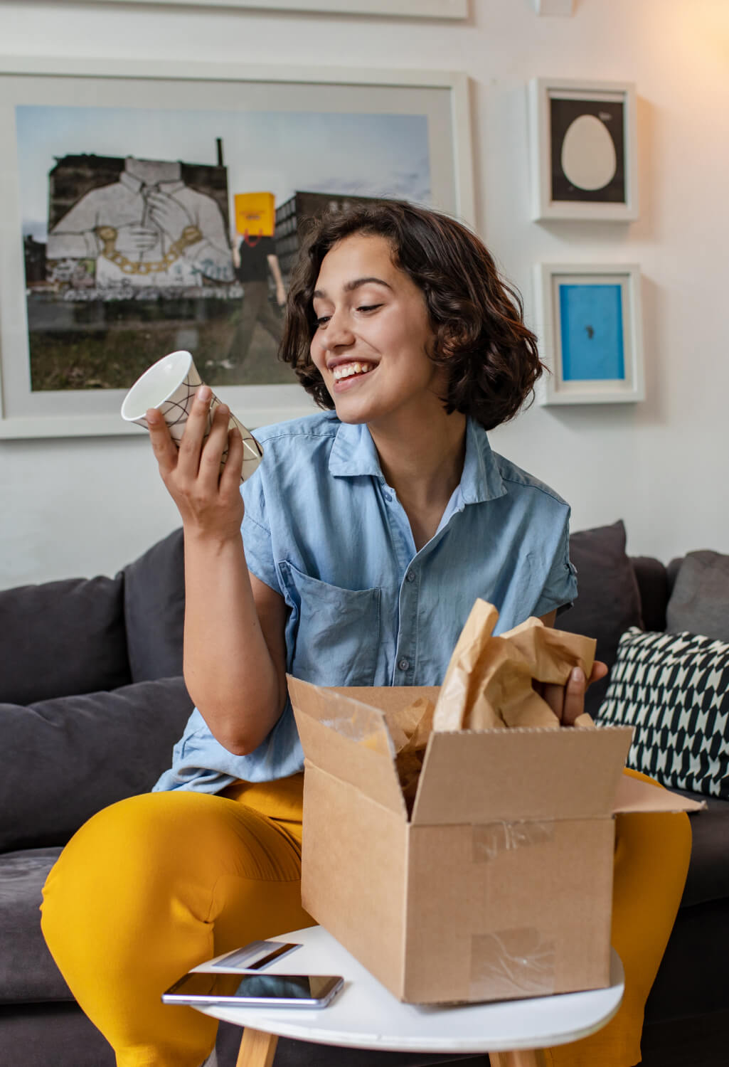 Woman sitting on a couch opening a box