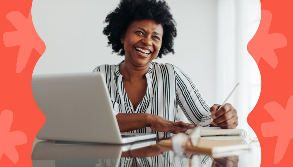 Woman sitting at a table taking notes on her laptop