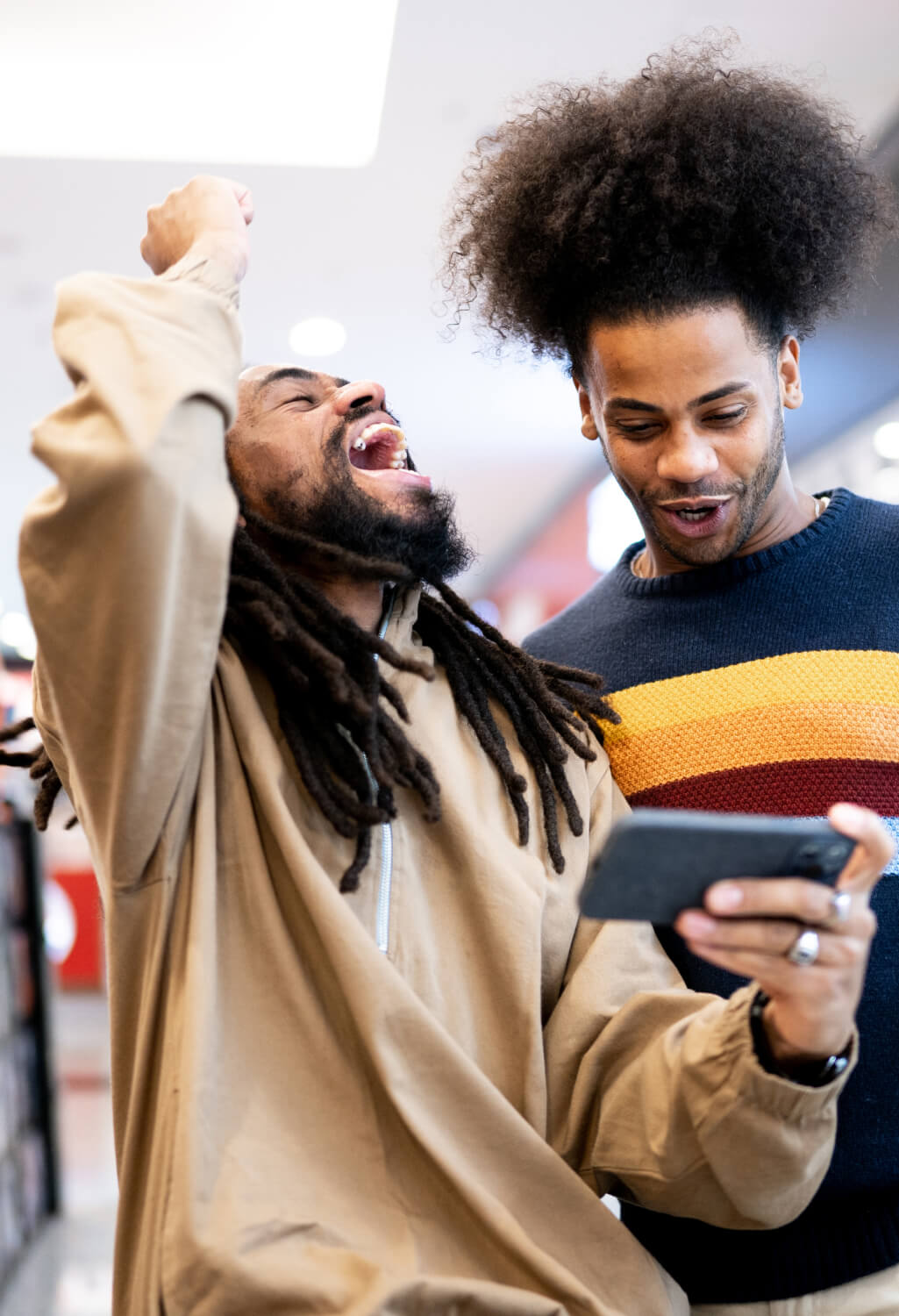 Two men laughing while looking at screen of cell phone