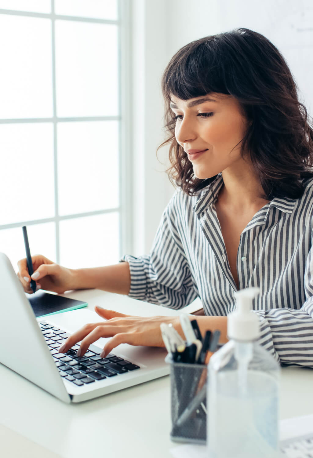 Woman taking notes on a tablet and her laptop