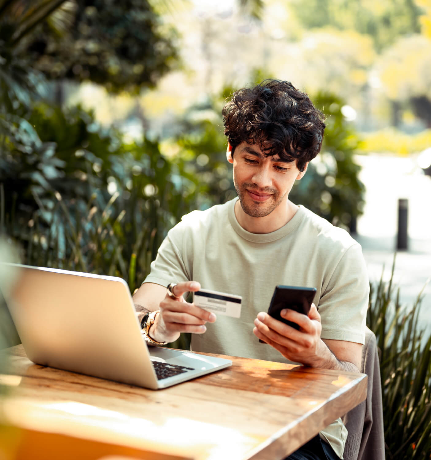 Man sitting outdoors, holding his phone, credit card