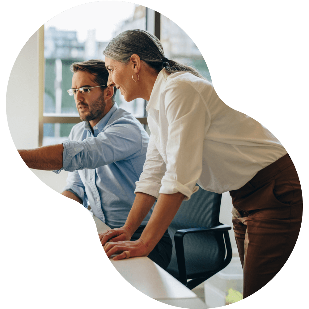 Man sitting at office desk with woman standing