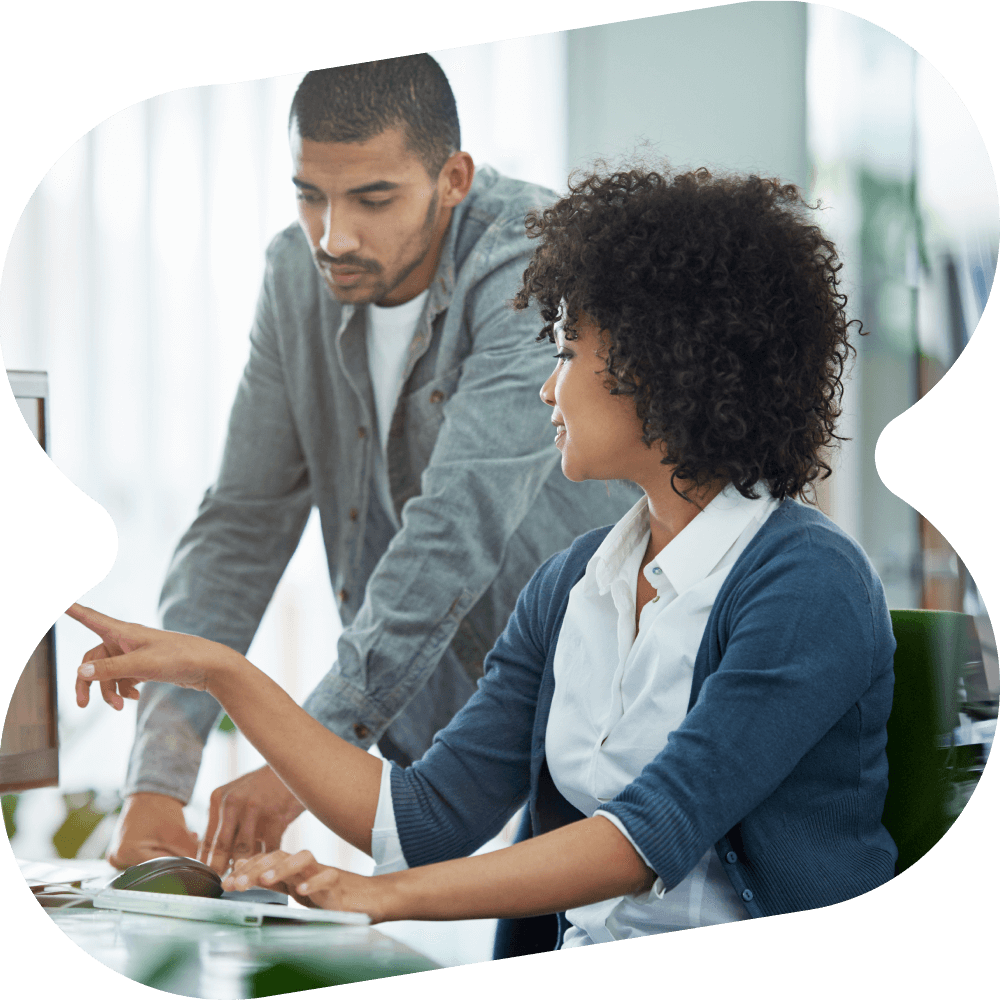 Woman sitting at desk with man standing behind her