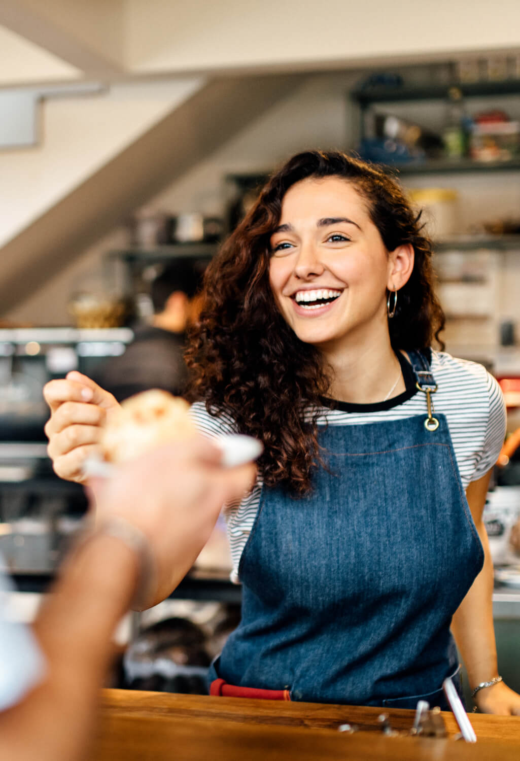 Woman smiling working behind counter in a coffee shop