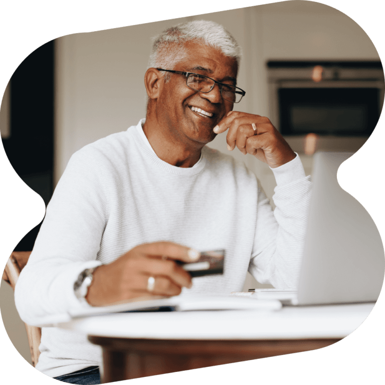 Man holding a credit card laughing at his laptop