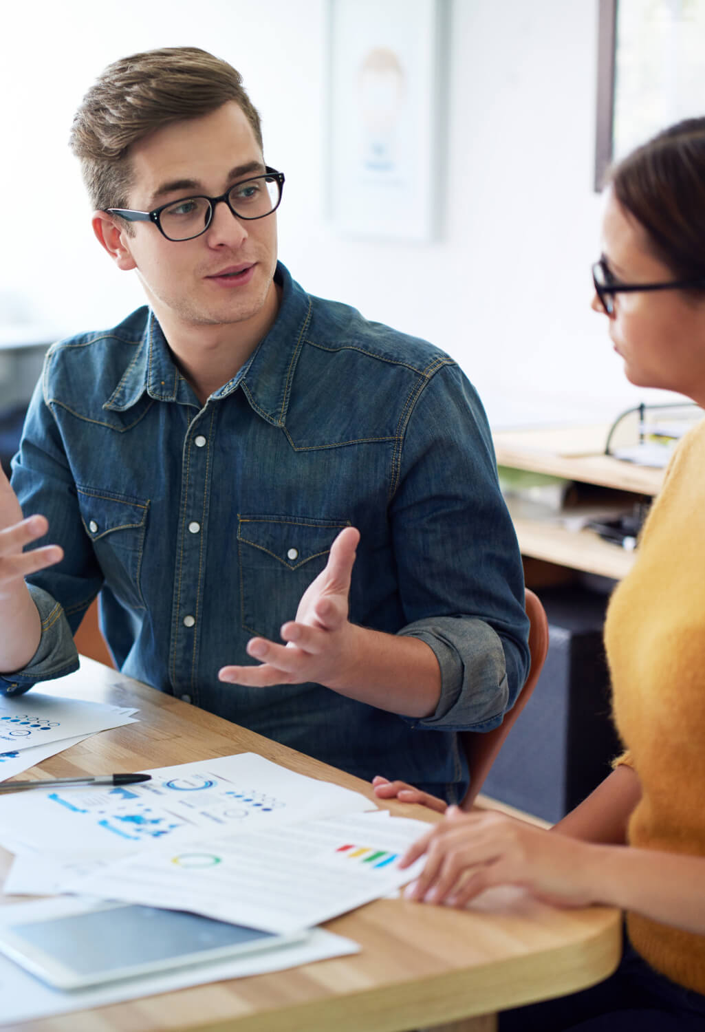 Young man and woman conversing over paperwork