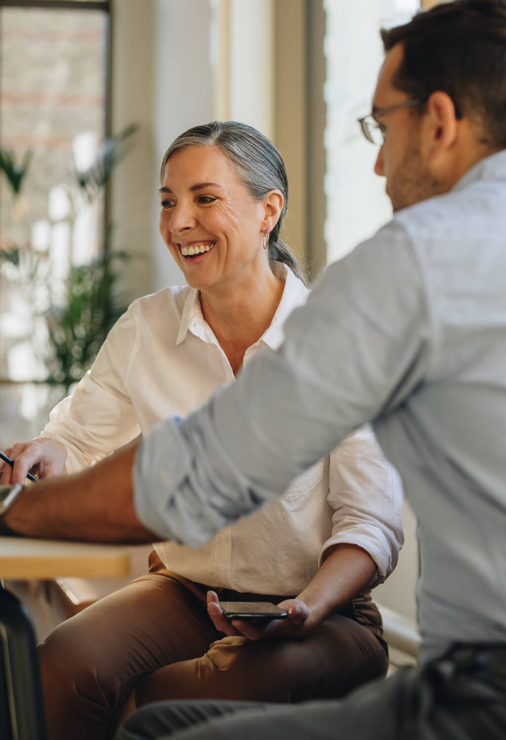 Man and woman conversing and viewing laptop at table