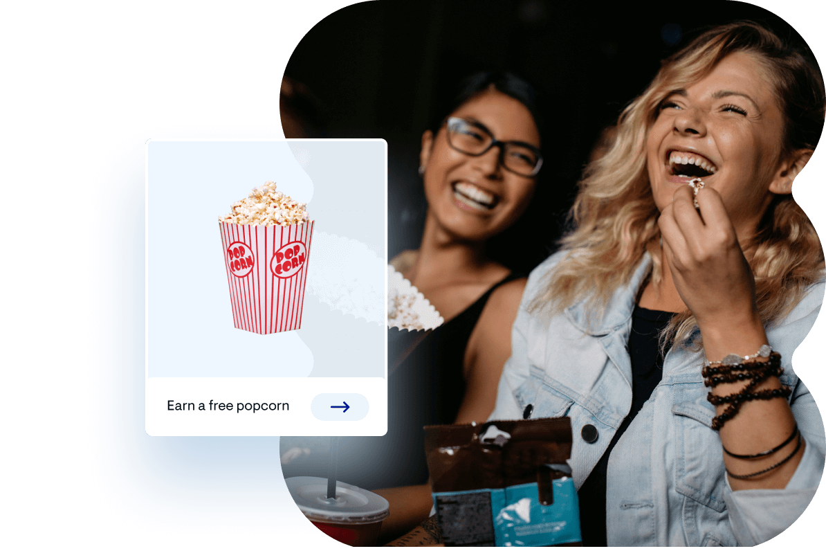 Women laughing and smiling eating in a movie theater