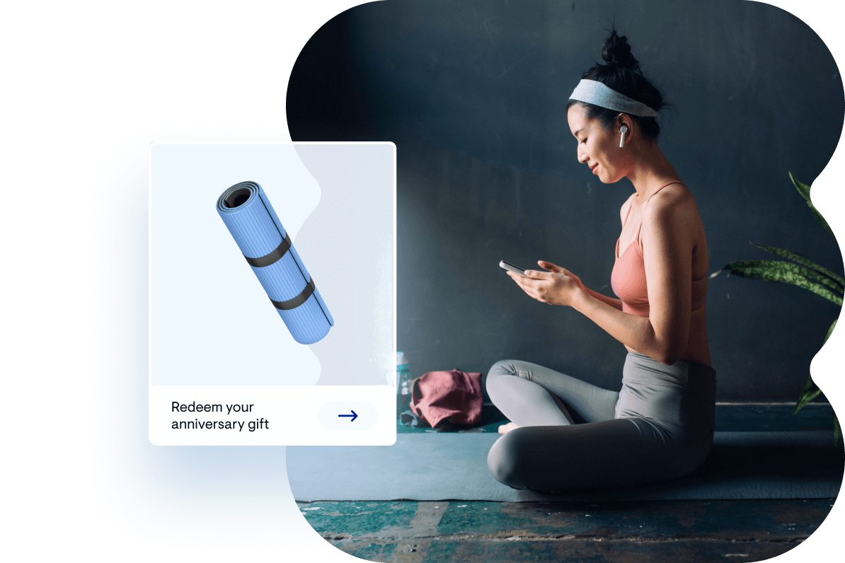 Woman sitting on yoga mat inside reading phone